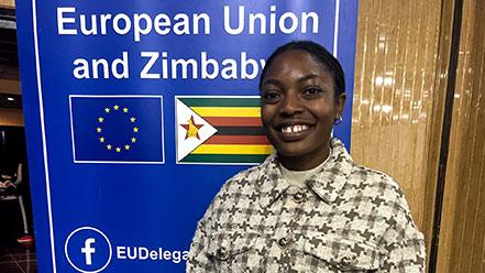 Young woman standing in front of a banner