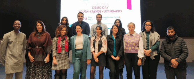 Group of individuals standing in front of a presentation screen at the "DEMO DAY Youth-Friendly Standards.