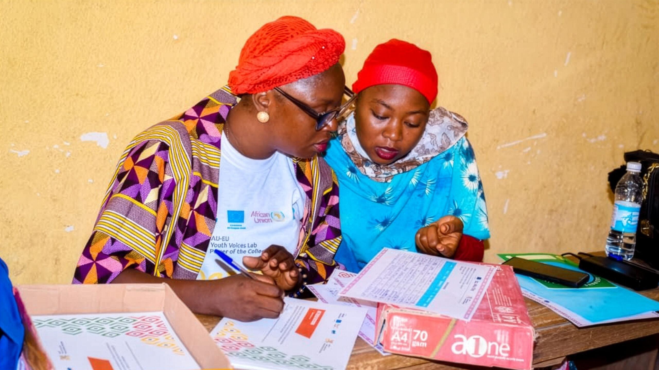 Two people at the Youth Forum on Peace and Governance in Maroua, reviewing printed documents together.